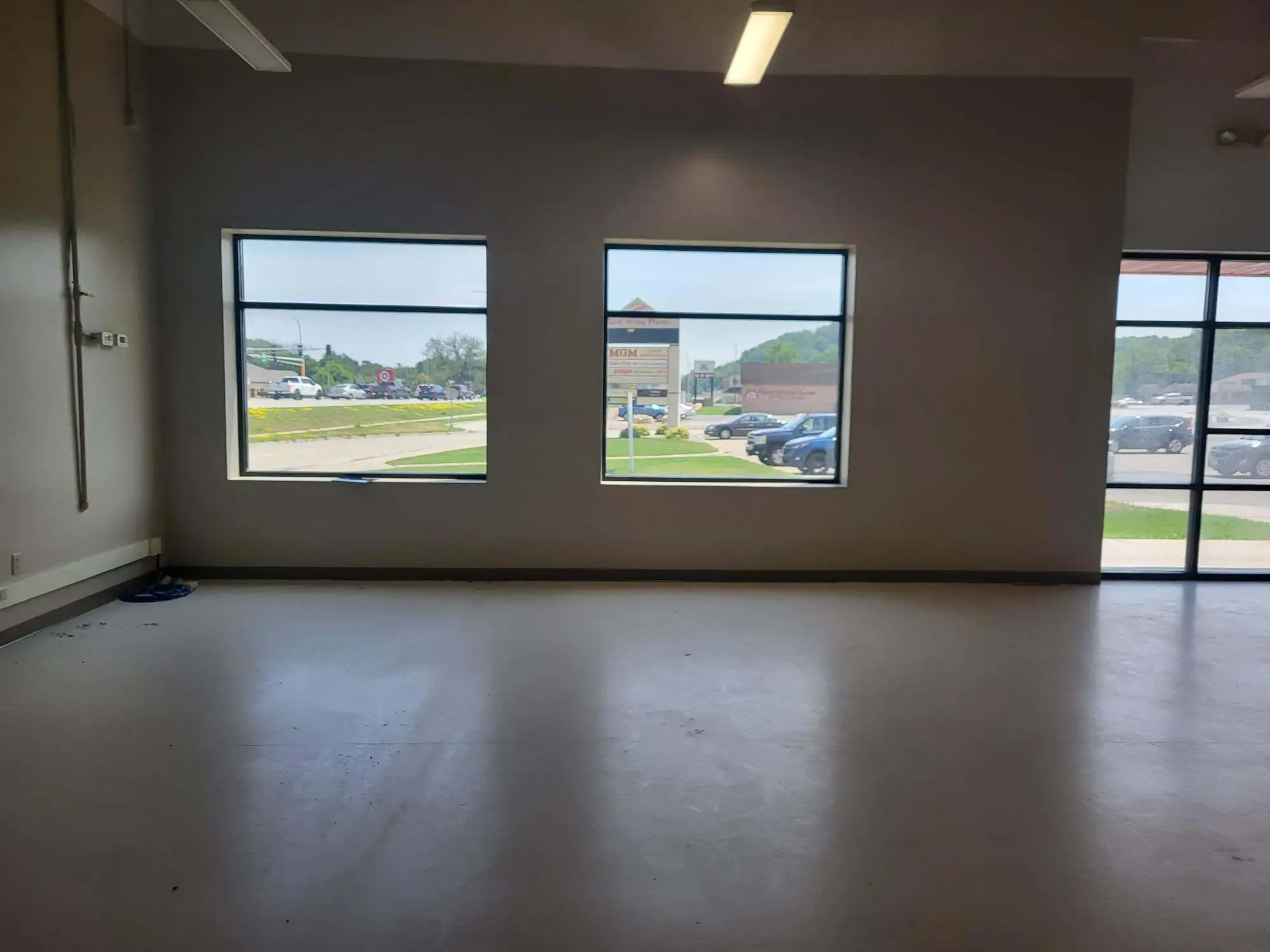 inside an empty office space looking through the front windows at a busy parking lot
