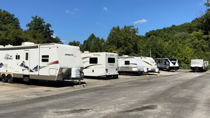 A row of uncovered campers at a storage facility.