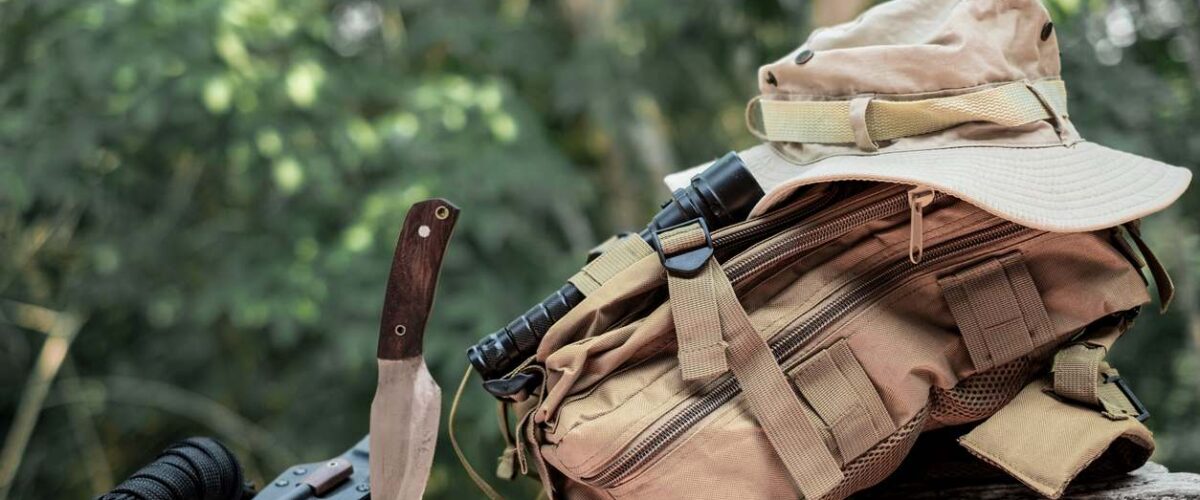 A hunting knife and bag sit on a log during hunting season.