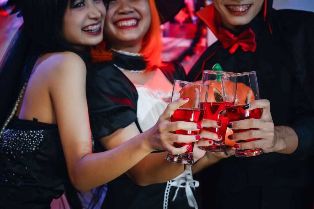 A group of friends in Halloween costumes enjoying a spooky soiree with their bloodred beverages.