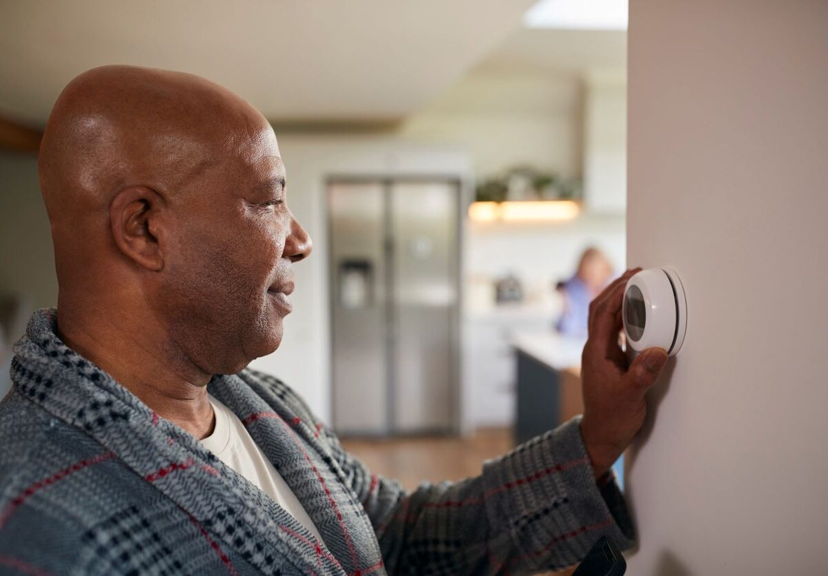 A man adjusts the smart thermostat in his home to save energy during winter.