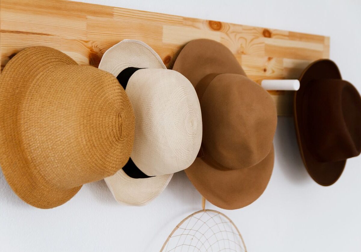 A group of hats hanging on a wooden board.