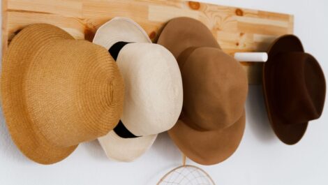 A group of hats hanging on a wooden board.