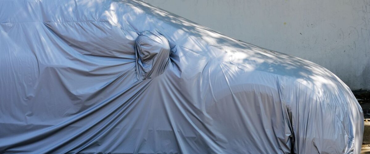 A car sits covered in a durable cover while parked in vehicle storage