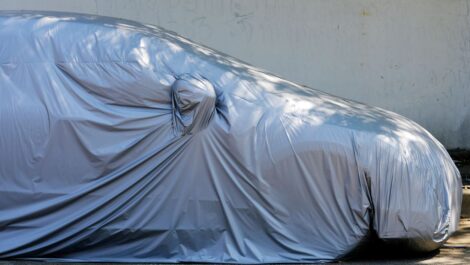 A car sits covered in a durable cover while parked in vehicle storage