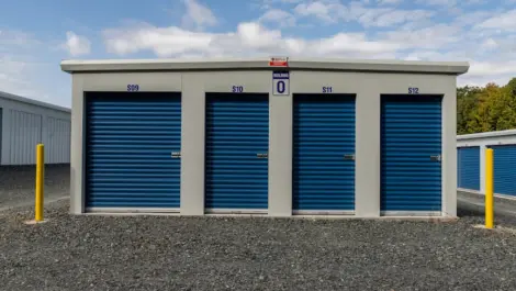 Front view of outdoor storage units with roll-up doors and asphalt driveway.