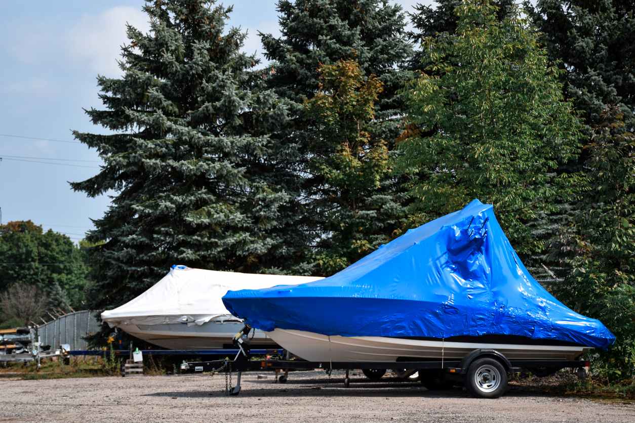 Two covered boats sit prepared for vehicle storage at a self storage facility.