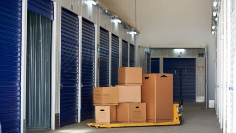 A series of closed storage units, with a pallet of cardboard boxes next to one open unit.